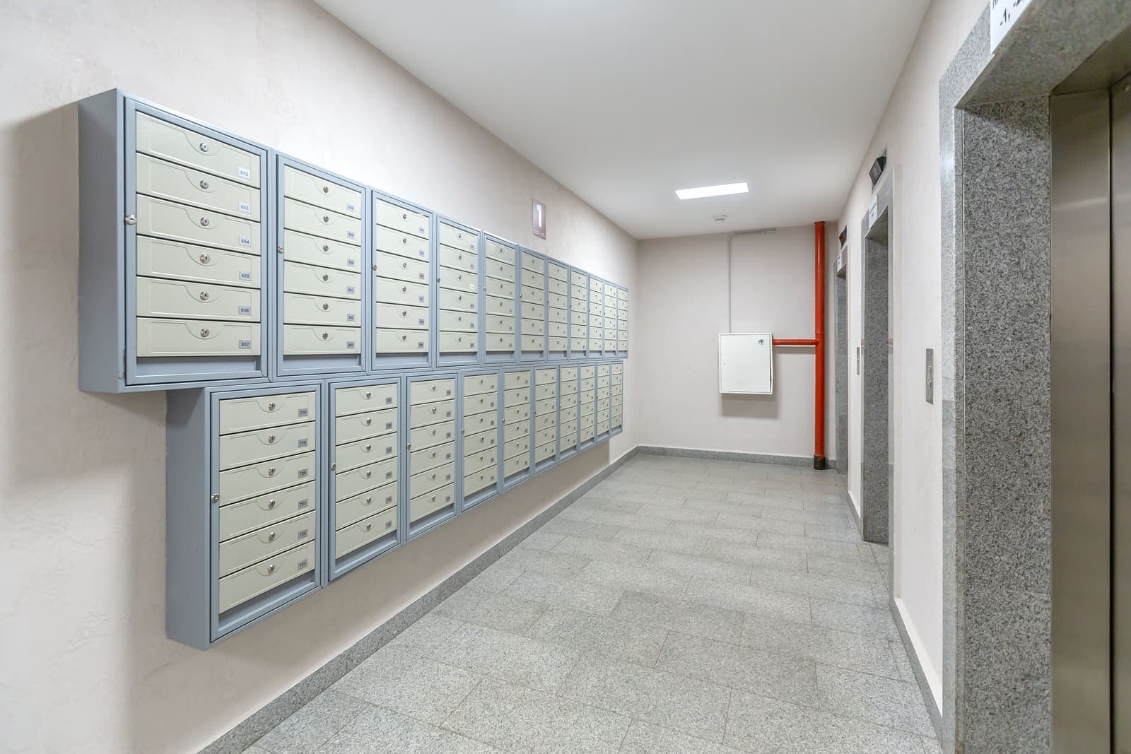 Hall d'entrée de copropriété propre avec boîtes aux lettres