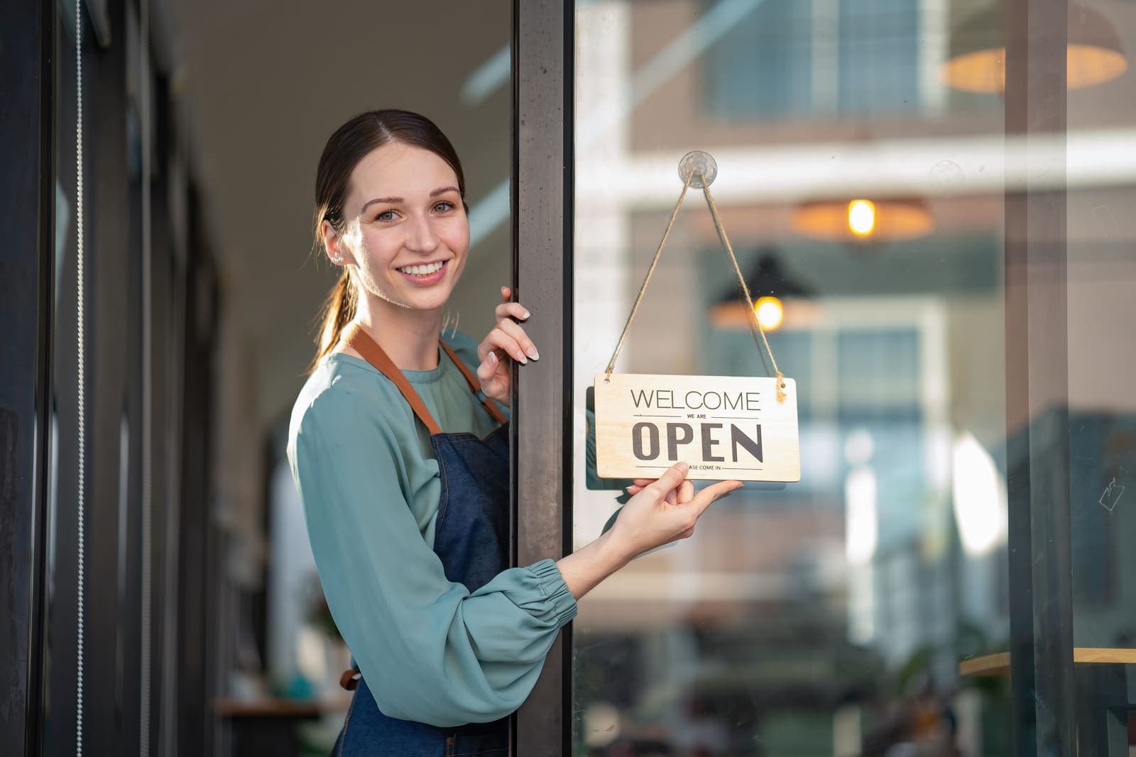 Commerçante devant la porte vitrée de sa boutique